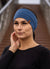 Woman wearing a blue headband with a brand logo, standing outdoors.