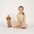 Smiling child sitting on the floor in beige bamboo long-sleeve top and bottoms.