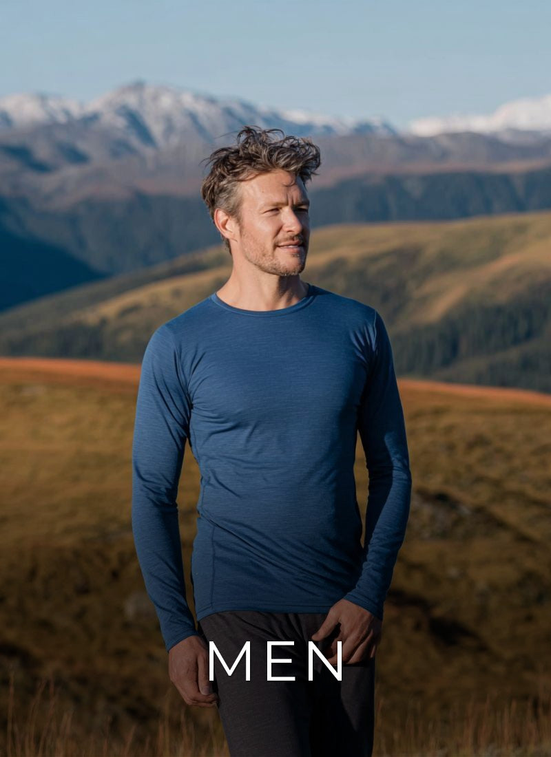 Man wearing a blue long-sleeve shirt standing in a mountainous landscape with 'MEN' text overlay.
